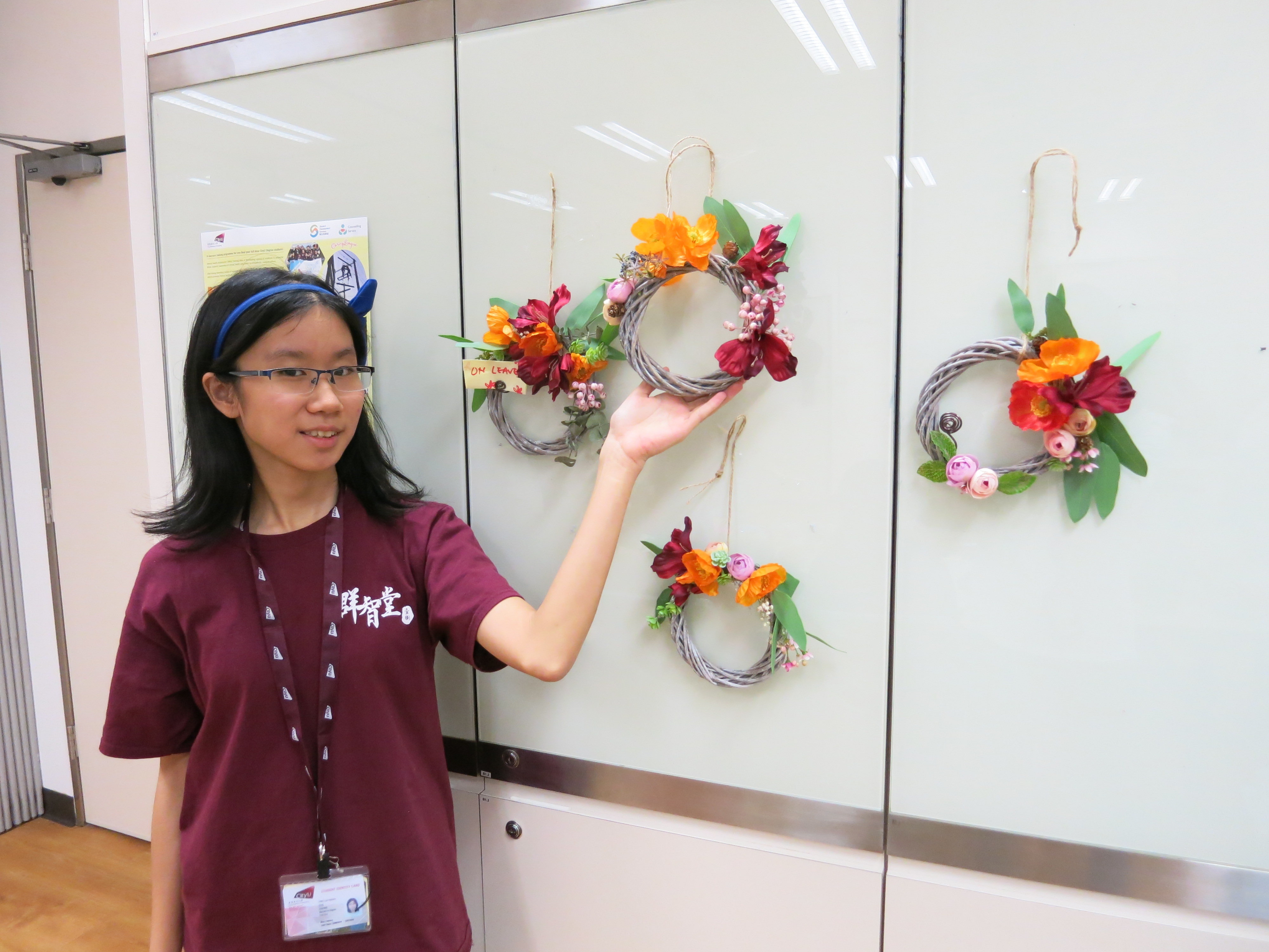 A photo of a student and her flower wreath. 
