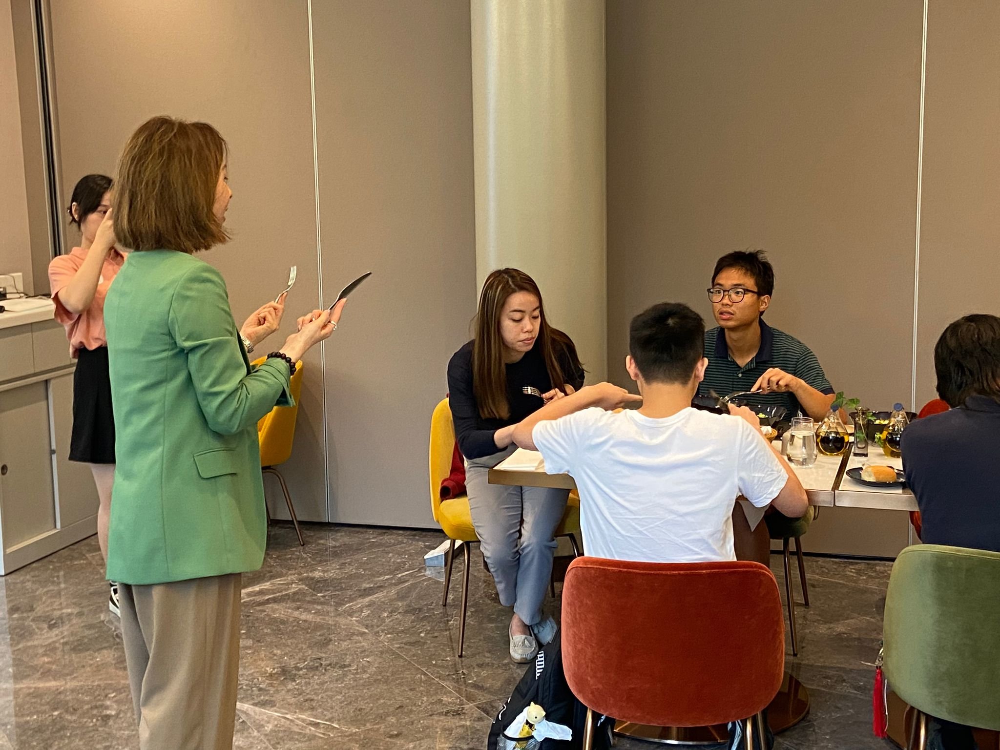 The instructor is demonstrating how to handle different utensils.導(dǎo)師正在示范如何拿握不同的餐具。