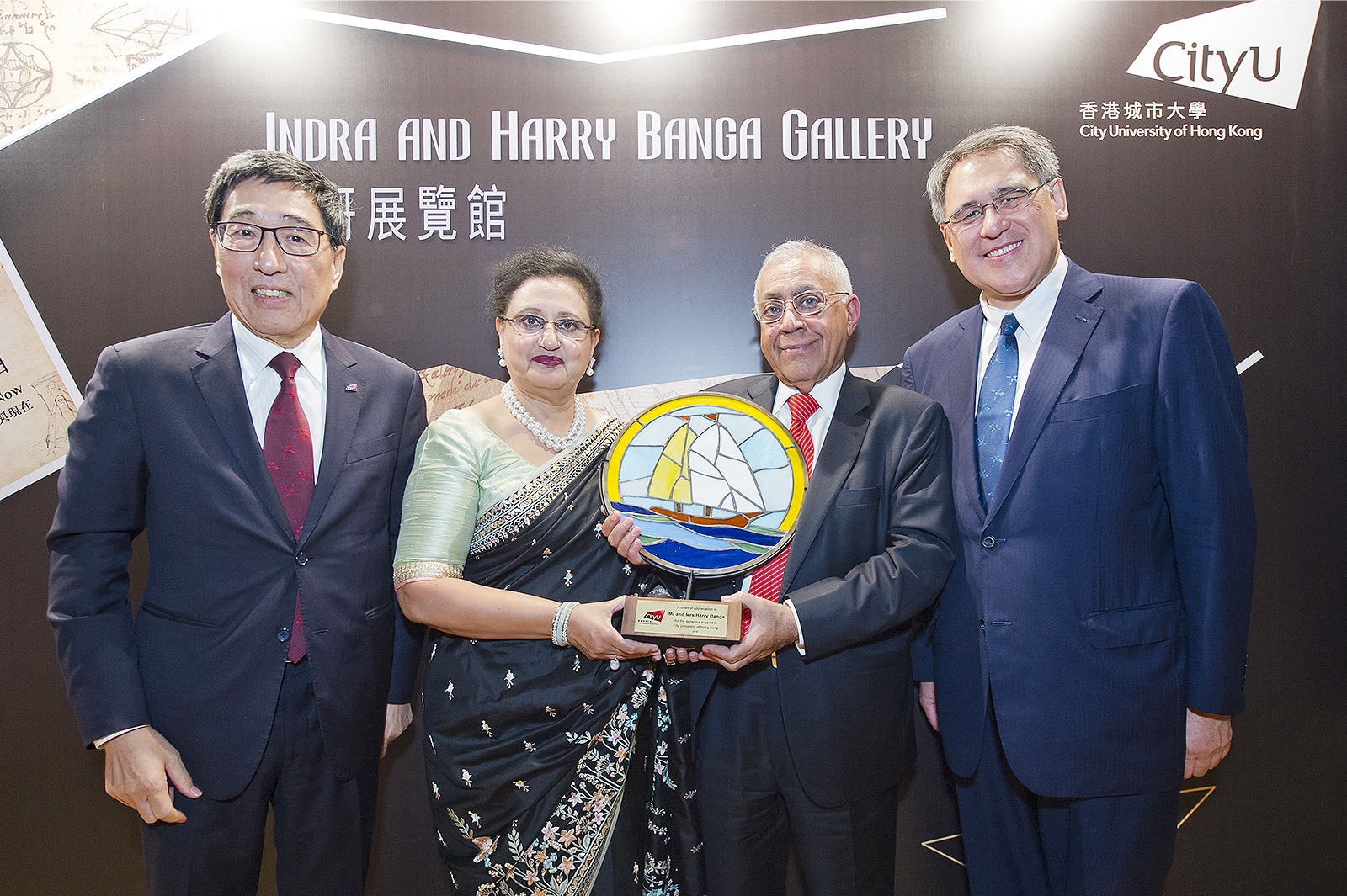 President Kuo (1st left) and Mr Huang (1st right) present a tailor-made souvenir to Mr and Mrs Banga (centre). This handcrafted artwork of a sailing ship represents leadership in Mr and Mrs Banga’s career, captainship in their family, and their friendship with CityU.